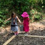 Two girls walking a plank path while holding hands