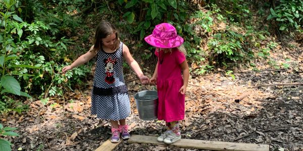 Two girls walking a plank path while holding hands