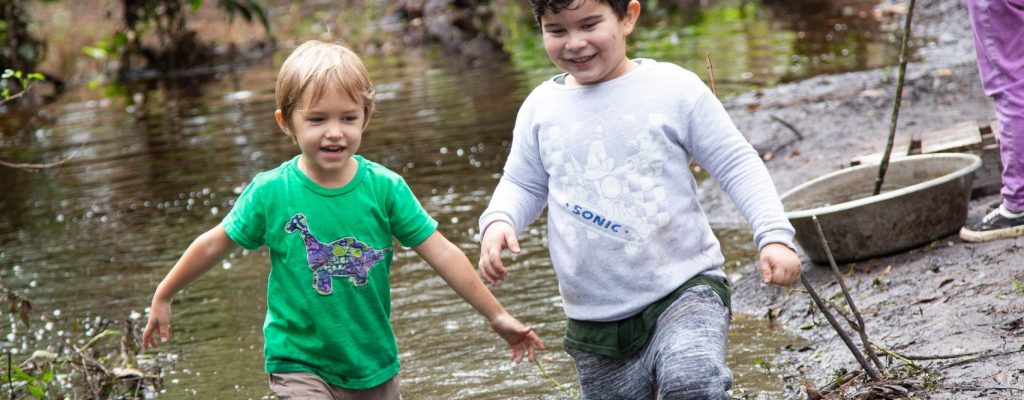 Central Florida Outdoor Therapy and Play: two boys walking through the seasonal creek at Treeline Enrichment