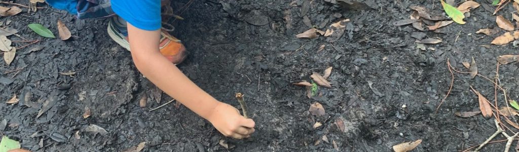 child writing in the dirt