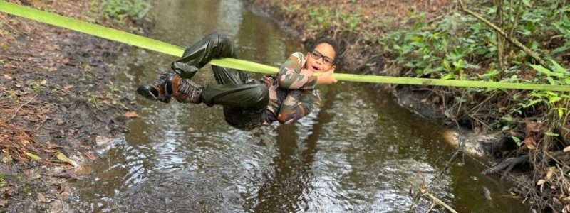 child hanging on rope over creek