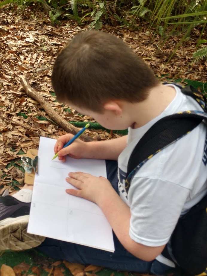 boy writing in a journal outside