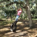 outdoor play - girl standing on tire swing